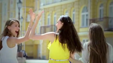 Üç neşeli kız, şık kıyafetler giyiyorlar, canlı butiklerin önünden geçiyorlar, kahkahaları havada yankılanıyor. Ellerindeki alışveriş torbaları ve yüzlerindeki gülücüklerle kaygısız arkadaşlığın ve modaya uygun eğlencenin özünü somutlaştırıyorlar.