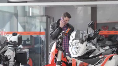 Şık bir esmer adam canlı bir galeride şık bir motosikletin yanında dururken bir telefon görüşmesi yapıyor. Motosiklet koltuğuna nazikçe dokunuyor, bu dinamik ortamda uzmanlığını ve motosiklet tutkusunu sergiliyor.