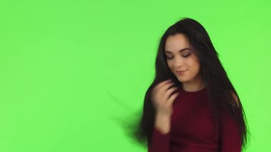 Çekici, genç, esmer bir kadın şen şakrak, yeşil bir fonda poz verirken neşe saçıyor. Uzun saçları zarifçe dökülüyor. Cilveli bir gülümseme ve gözlerindeki ışıltıyla gençliğin coşkusunu ve özgüvenini somutlaştırıyor, seni davet ediyor.