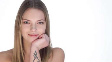 Uzun, dalgalı saçları olan çarpıcı beyaz bir kadın, el değmemiş beyaz bir arka planda ışıltılı bir gülümsemeyle dövmesini işaret ediyor. Kusursuz cildi ve zarif tavrı saf güzelliğin vücut bulmuş hâli. Hayranlık uyandırıyor.