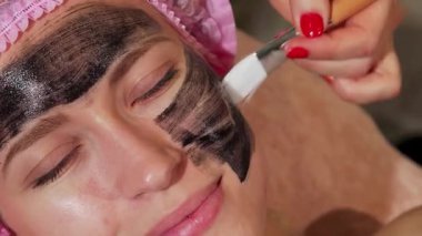 Sakin bir kadın, yetenekli bir kozmetikçi olarak doğal güzelliğini arttırmak için siyah bir maske takar. Yumuşak ışıklandırma ve rahatlatıcı renklerle güzellik kliniğinin samimi ortamı gençleşmek için sakin bir ortam yaratıyor.