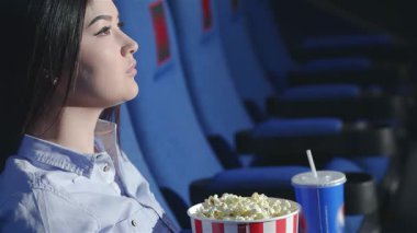 Elinde bir kova tereyağlı patlamış mısır tutan hevesli bir Asyalı kız canlı bir sinema ortamında başparmağını kaldırıyor. Etrafı arkadaşlarla çevrili olan atmosfer, aperatiflere daldıkları ve tebessümlerini paylaştıkları için heyecanla uğulduyor.