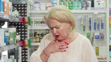 Görünüşte sıkıntılı ve alnını tutan yaşlı bir kadın kalabalık bir eczane koridorunda ilaç arıyor. Etrafı renkli sağlık ürünleriyle dolu raflarla çevrili kadın, hastalığından kurtulma mücadelesini somutlaştırıyor.