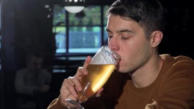 Çekici bir genç adam ferahlatıcı bir bira içmekten zevk alır, barda biraz dinlenir. Barın ılık atmosferi, yumuşak ışıklandırması ve rahat atmosferiyle, boş zamanlarını artırarak, günlük koşuşturmadan mükemmel bir kaçış sağlıyor.