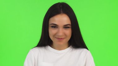 Siyah saçlı, neşeli genç bir kadının yakın plan portresi. Coşkulu bir şekilde mutluluk saçıyor. Parlak yeşil arka plan onun neşeli ifadesini artırıyor, pozitifliği ve başarıyı simgeliyor.