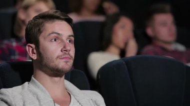 Odaklanmış genç bir adam lüks bir sinema koltuğunda oturur, perdede anlatılan sürükleyici hikayeye kendini tamamen kaptırmıştır. Etrafını saran arkadaşlar patlamış mısır ve gazozu paylaşıyor. Kahkaha ve heyecanla dolu canlı bir atmosfer yaratıyorlar.