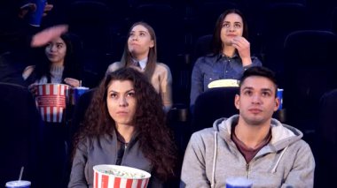 Koyu renk saçlı genç bir adam, rahat sinema koltuklarında güvenle yürür. Filmin tadını çıkarmaya hazırdır. Etrafı çeşitli arkadaşlarla çevrili olan atmosfer, patlamış mısır ve içeceklerle dolup taşıyor.