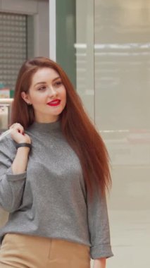 Parlak kumral saçlı ve parlak kırmızı dudaklı genç bir kadın kameraya kendinden emin bir şekilde gülümsüyor. Elinde şık beyaz alışveriş torbaları var. Bu canlı sahne perakende terapisinin heyecanını özetliyor. Modayı takip eden kıyafetini ve coşkuyu vurguluyor.