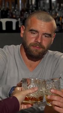 Neşeli, olgun bir adam, neşeli bir bar sahnesinin kahkahalarını ve arkadaşlığını paylaşan arkadaşlarıyla kadeh kaldırır. Bar ışıklarının sıcaklığı ve bardakların tıkırtısı davetkar bir atmosfer yaratıyor.