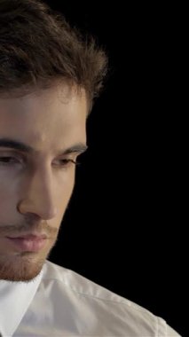 Gıcır gıcır beyaz gömlekli ve parlak siyah kravatlı ciddi bir beyaz adam, çarpıcı bir siyah arka plan karşısında, kulaklığından dikkatle dinliyor. Onun yoğun bakışları ve ince vücut dili özgüven ve uyanıklık yayıyor, özünü somutlaştırıyor.