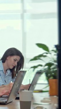 Kendini işine adamış, şık çizgili bir gömlek giymiş genç bir kadın, parlak, havadar bir ofiste yeşilliklerle çevriliyken dizüstü bilgisayarına konsantre oluyor. Doğal ışık ve saksı bitkisiyle güçlendirilmiş canlı atmosfer yaratıcılığı ve üretkenliği teşvik eder.