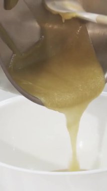 Yetenekli bir pasta şefi, tatlı yaratma sanatını somutlaştıran pırıl pırıl bir tavadan lekesiz beyaz bir kaseye zarif bir şekilde sıcak krema döker. Bu yakın çekim kremin pürüzsüz, akışkan dokusunu yakalar, şefin hassasiyetini vurgular ve...