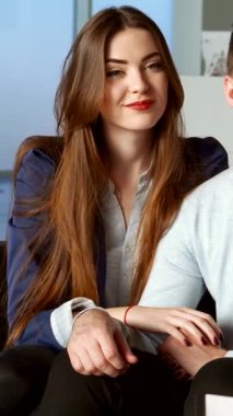 Neşeli, genç, beyaz bir çift, şık sakallı bir adam ve mutluluk saçan bir kadın, modern bayilikte bir satıcıya hevesle bağlanıyor. Onların parlak gülümsemeleri ve hareketli hareketleri davetkar bir atmosfer yaratıyor.