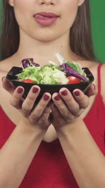 Nefis dudakları olan, baştan çıkarıcı genç bir kadının canlı bir kase taze salatayı yalarken baştan çıkarıcı bir görüntüsü. Bu çekici görüntü, sağlık ve şehvetin bir karışımını yayıyor, izleyicileri lezzetli bir besleyicinin tadını çıkarmaya davet ediyor.