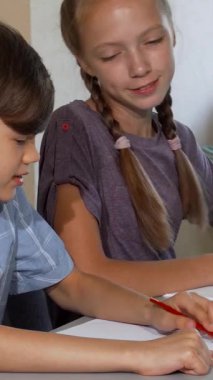 Canlı bir sanat sınıfında, şık saç kesimi olan neşeli bir çocuk ve neşeli örgülü yaratıcı bir kız, renkli fikirlerini kağıda dökerken aynı anda kahkahaları paylaşıyor. Canlı ifadeleri ve odaklanmış enerjileri güzelliği vurguluyor.