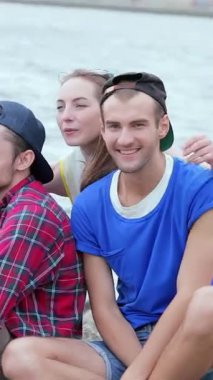 Üç hayat dolu genç arkadaş, köpüklü su kenarında, hepsi mutlulukla ışıldarken sevinçle arkadaşlarına sarılan bir kızla yürek ısıtan bir anı paylaşıyor. Bu canlı sahne arkadaşlığın ve kaygısız yaz maceralarının ruhunu özetliyor.