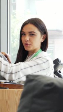 Canlı genç bir bayan tasarımcı, güneşli modern bir ofiste meslektaşı ile tutkuyla bir tişört tasarımını tartışırken coşku saçıyor. Sahne, yaratıcılığın ve moda endüstrisindeki takım çalışmasının dinamik enerjisini güzel bir şekilde yakalıyor.