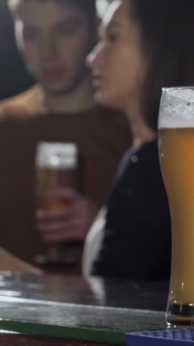 Cilalı tezgahın üzerinde güzel işlenmiş bir bira bardağı parıldarken, neşeli bir grup arkadaş şen şakrak bir barda kadehlerini şaklatıyorlar. Bar ışıklarının sıcacık parlaklığı herkesi rahatlamaya çağıran samimi bir ortam yaratıyor.