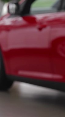 Rahat bir süveter içinde şık bir genç kadın parlak ve modern bir bayide şık bir model arabayı zevkle inceler ve otomotiv tercihleri için heyecan saçar. Parlak araçlar ve çağdaş tasarım ile süslenmiş canlı sergi salonu onu geliştirir.
