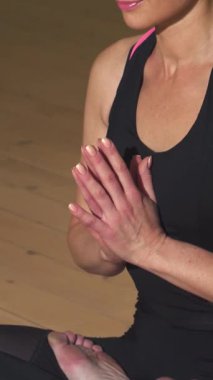 Mutluluk dolu, gözleri kapalı bir kadının yakın çekimi, yoga stüdyosunda meditasyon yaparken gülüşü huzuru yansıtıyor. Yumuşak ışıklandırma ve dingin çevre onun rahatlama ve iç huzur atmosferini yükseltir, izleyicileri kucaklamaya davet eder.