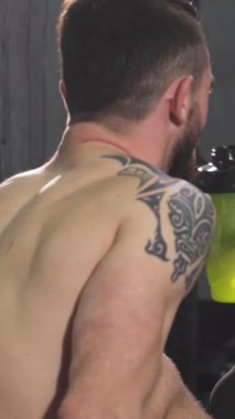 İki zinde genç adam, bir üstsüz, çarpıcı bir dövme sergiliyor, yoğun bir çalışmadan sonra yürekten bir kahkaha paylaşıyorlar. Enerjik arkadaşlıkları enerji ve motivasyon yayarak dinamik bir spor salonunda dostluk ve zindeliğin özünü yakalıyor.