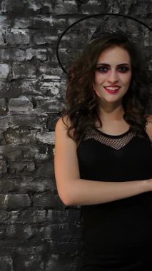 Büyüleyici bir büyücü, sırıtan bir balkabağını şakayla tutarken baş parmağını kaldırarak siyah tuğladan bir duvara karşı güven yayar. Bu Cadılar Bayramı temalı görüntü tuhaf ama gizemli bir titreşim yayıyor. Büyünün elementlerini harmanlıyor.