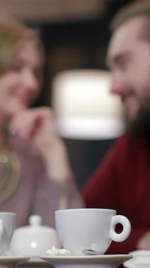 Sevimli genç bir çift, hoş bir sevgililer günü kutlamasında sıcak bir kafede, aromatik kahve ve çay yudumlayarak eğleniyor. Ortak gülüşleri ve şefkatli bakışları büyüleyici bir ortam yaratıyor, unutulmaz romantik bir yemek randevusu için mükemmel.