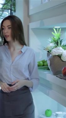 Renkli çiçek vitrinleriyle büyülenmiş iki şık kadın, enfes bir çiçekçide dolaşıyorlar. Şık mavi bir bluz giyen zarif çiçekçi, neşeli arkadaşına dalgalı saçlarıyla baş döndürücü beyaz bir çiçek sunar.