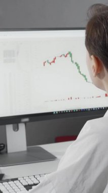 Kendine güvenen kırmızı dudaklı bir borsa simsarı kameraya parlak bir şekilde gülümsüyor, canlı piyasa verilerini parlak monitöründe analiz etmekle derinden ilgileniyor. Renkli çizelgeler ve grafikler onun hırsını ve uzmanlığını yansıtıyor.