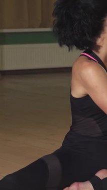 Çarpıcı bir kadın vücudunu zarif bir şekilde kapalı bir alanda geriyor yoga pratiği yoluyla güç ve dinginlik yayıyor. Sıcak ahşap zemin ve yumuşak ortam aydınlatması huzurlu bir cennet yaratıyor, izleyicileri refahı kucaklamaya çağırıyor.