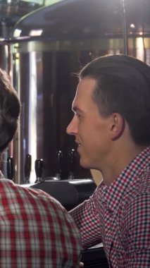 Sıcak bir gülümsemesi olan çekici bir barmen, neşeli bir barda neşe saçan ve yoldaşlık saçan iki müşteri için ferahlatıcı el yapımı biraları ustalıkla doldurur. Neşeli atmosfer, kahkahalarla ve bardakların şıngırtısıyla dolu.