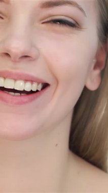 Bu büyüleyici yakın plan çekimde beyaz tenli güzel bir kadın el değmemiş beyaz bir fon karşısında kendine güven ve cazibe yayıyor. Onun nazik gülüşü ve taze gençlik parıltısı doğal güzelliğin ve cilt bakımının özünü somutlaştırıyor.