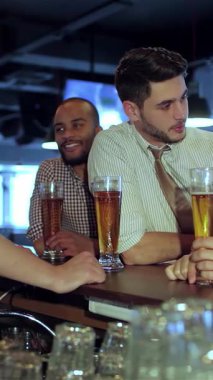 Dört genç iş adamı, neşe saçıyor, neşeli bir barda kahkaha ve tezahürat yapıyorlar, kutlama için bardaklarını tokuşturuyorlar. Büyük ekranda en sevdikleri futbol takımı için coşkuyla tezahürat yaparken elektrik atmosferi heyecanla uğulduyor.