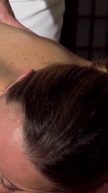 Huzurlu bir kadın, yenilenen bir sırt masajının mutluluğunun tadını çıkarıyor. Yetenekli bir masör, cildine nazikçe çalışırken, ışıl ışıl gülüşü, saf rahatlığı yansıtıyor. Sakinleştirici aromalar ve hafif ışıklandırmayla bezenmiş sakin bir spa atmosferi onu sarar.