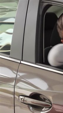 Işıldayan genç bir adam, gösterişli ve modern arabasının anahtarını muzaffer bir şekilde elinde tutarak sürücü tarafındaki pencereden sarkıyor. Bu heyecan verici an, başarılı bir alışverişin neşesini, heyecan saçan heyecanı ve yeni maceraların vaadini özetliyor.