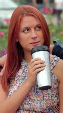 Neşeli bir çift, güneşli bir park bankında, canlı güllerin arasında, parlak fincanlardan aromatik kahve yudumluyor. Neşeli gülüşleri ve şefkatli kucaklaşmaları sıcaklık ve bağlantı yayarak hoş bir atmosfer yaratıyor.