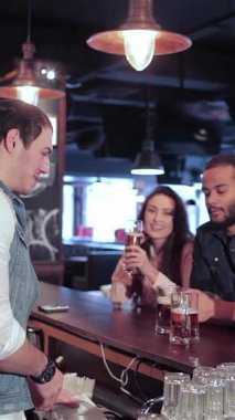 Canlı bir bar sahnesinde iki neşeli kadın ve kadeh kaldıran bir adam dostluğu ve güzel zamanları kutluyorlar. Atmosfer heyecanla uğulduyor, sıcak ışıklarla aydınlatılıyor, içkilerinin keyfini çıkarırken aynı zamanda tezahürat yapıyorlar.