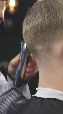 Kendini işine adamış, detaylara meraklı bir berber, bir adamın saçını şekillendirmek için ustalıkla elektrikli makas kullanır, yeni ve şık bir görünüm yaratır. Sıcak ışıklandırma ve klasik dekor ile berber dükkanının cazip ambiyansı, tımar sanatını geliştirir.