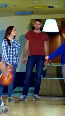 Bir grup arkadaş neşeli bir beşlik çakar ve sarışın bir adam güvenli bir şekilde kırmızı bowling topunu aşağı yuvarlar ve zaferin heyecanını yakalar. Bowling salonundaki bu enerjik sahne genç yetişkinler arasında kahkaha ve dostluk yayıyor.