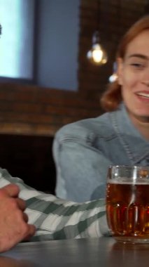 Tarz sahibi genç bir kadın ferahlatıcı bir içkiden zevk alır, bir yudum alırken gözleri zevkle ışıldar. Yumuşak ışıklandırmayla süslenmiş samimi bar ortamı arkadaşlarla sosyalleşmek ve kutlamak için mükemmel bir ortam yaratıyor.