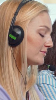 Her biri parlak kulaklıklarla süslenmiş genç profesyonellerden oluşan dinamik bir grup canlı bir çağrı merkezinde hareketli tartışmalara girişiyor. Kadın teknik destek operatörünün ve meslektaşlarının parlak gülümsemeleri hayat dolu bir atmosfer yayıyor.