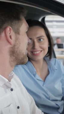 Genç bir çift, gülümseyen beyaz bir erkek ve kadın galerideki şık bir arabanın içinde hoş bir sohbet ediyorlar. Birlikte geleceklerini hayal ederken gözleri heyecanla parıldıyor. Parlak, modern tasarımla çevrili.