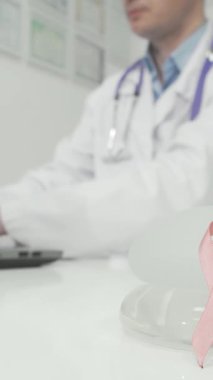 Çarpıcı bir sahnede göğüs kanseri farkındalığını sembolize eden pembe bir kurdele parıldayan bir doktor masasında silikon göğüs implantlarının yanına yerleştirildi. Bu güçlü görüntü, sağlığın, önlemenin ve