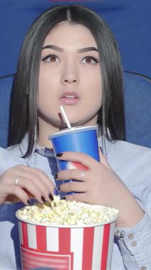 Düşünceli Asyalı bir kadın canlı bir tiyatroda tek başına oturuyor. Patlamış mısır yiyip gazoz yudumlarken gözleri merakla bakıyor. Canlı mavi koltuklar ve parlayan ekran büyüleyici bir ortam yaratarak onu sinema büyüsü dünyasına davet ediyor.