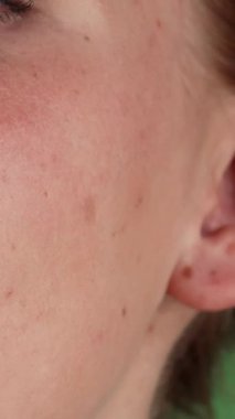 Göz kamaştırıcı bir yakın plan, büyüleyici yeşil gözleriyle neşeli kızıl saçlı bir kadın yakalıyor. Işıl ışıl gülüşü, canlı yeşil renkli arka planı aydınlatıyor. Kusursuz cildi ve büyüleyici ifadesi güven ve mutluluk saçıyor. Seyircileri tadını çıkarmaya çağırıyor.