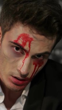 Büyüleyici bir vampir adam, yüzü çarpıcı bir şekilde dramatik kan çizgileriyle işaretlenmiş, gölgeli tuğla bir duvara karşı yoğun bir şekilde ruhuna bakıyor. Bu ürpertici portre, büyüleyici bir görsel ortamda cazibe ve korkuyu harmanlayarak Cadılar Bayramı 'nın özünü yakalıyor.