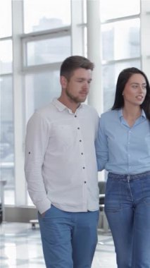 Gösterişli bir araba galerisinde el ele gezen şık, genç bir çift, sergilenen hayret verici araçlara hayranlıkla bakarken gözleri heyecandan parıldıyor. Şık mavi bir bluz ve uygun kot giyen esmer kadın, neşeli bir şey paylaşır.