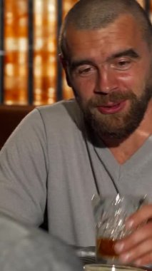 İyi bakımlı sakallı şık bir adam, lüks barın sıcak ve davetkar ışığında viski bardakları parlayan bir arkadaşıyla keyifli bir konuşma yapar. Zarif dekor ve canlı atmosfer, yoldaşlık ve başarı kutlamalarını güçlendirir.