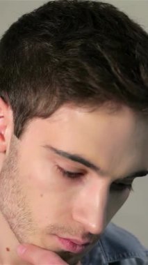 Modaya uygun kot pantolon giyen yakışıklı genç bir adam, desenli gri tuğlalı bir arka plana karşı düşünceli bir poz veriyor. Çekici bir gülümseme ve derin düşüncelere dalan bir bakışla, kendine güveni ve zarafetiyle, izleyicileri rahatlamış titreşimleriyle bağ kurmaya davet ediyor.