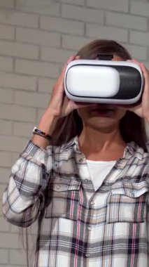 Uzun, dalgalı saçları olan hevesli genç bir kadın dijital macera dünyasına dalmış, zarif sanal gerçeklik kulaklığını zevkle ayarlıyor. Şık, modern ofis arkaplanına karşı kurulmuş enerjik enerjisi teknolojiye karşı bir tutku yayıyor.